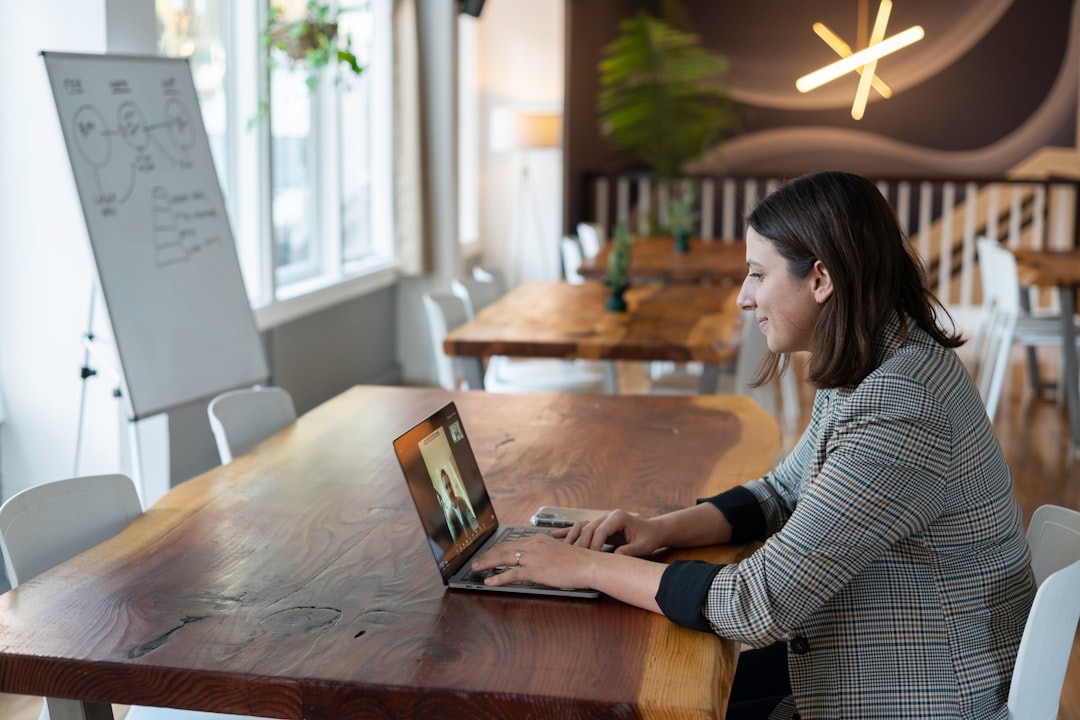 Woman on video call at a large live-edge wooden table.